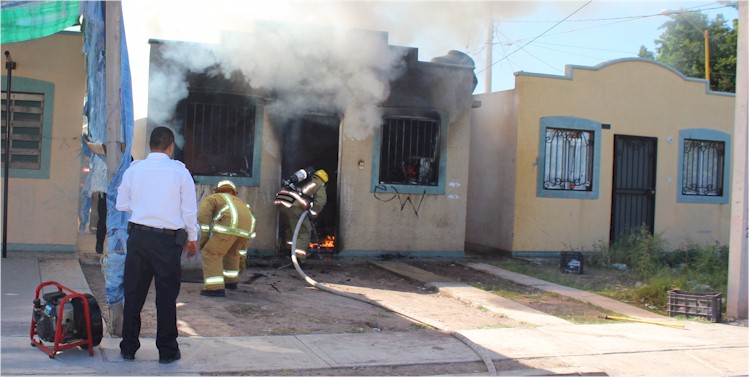 Bomberos ingresando a la vivienda completamente en llamas