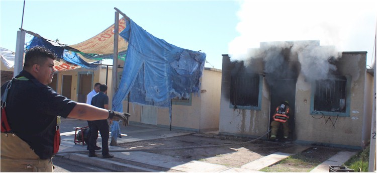 Maquinista dando instrucciones a los bomberos que ingresan a la vivienda incendiandose