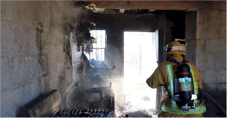 Bombero extinguiendo el fuego en el interior de la vivienda